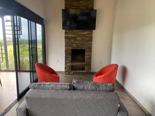 Cábaña bonita vista في Atemajac de Brizuela: غرفة معيشة مع أريكة وكرسيين حمراء