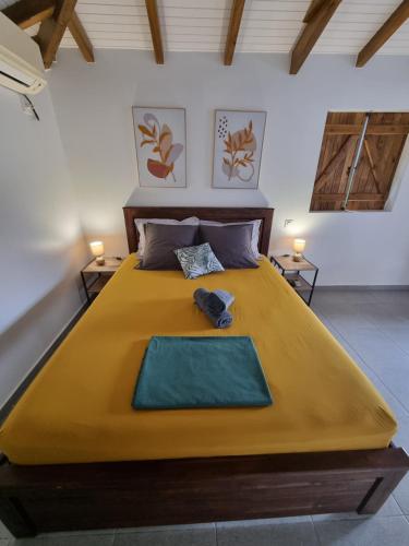 a bedroom with a large bed with a yellow blanket at Le Cataleya in Sainte-Rose