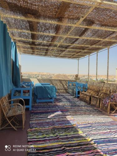 ein Zimmer mit Tischen und Stühlen und einem großen Teppich in der Unterkunft Nubian Hights guesthouse in Shellal