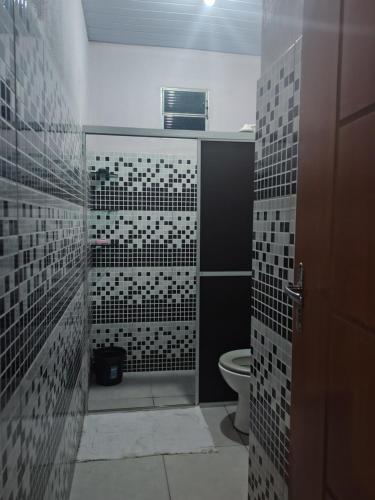 a bathroom with a toilet and black and white tiles at KL Residencial in Manaus
