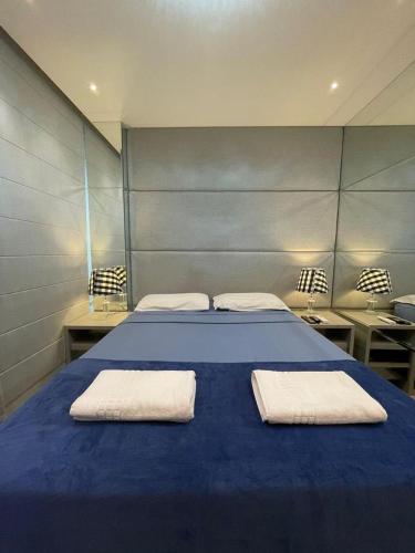 una camera da letto con un letto blu con due asciugamani sopra di Charmant Vertigo a Campo Grande