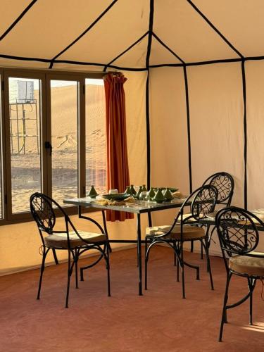 a dining room with a table and chairs in a tent at Arawan Luxury Desert Camp in Mhamid