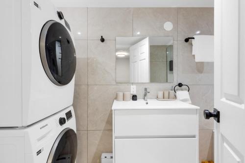 a white bathroom with a washing machine and a sink at Boho Luxe 2-Floor Retreat Sleeps 6 Private Patio in Montréal