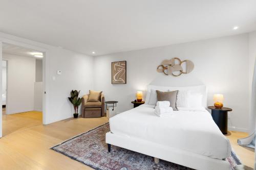 a white bedroom with a white bed and a chair at Boho Luxe 2-Floor Retreat Sleeps 6 Private Patio in Montréal