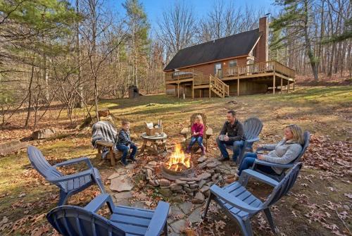 a group of people sitting around a fire in front of a cabin at Family-Friendly Home w Hot Tub Fire Pit Games in North Glade