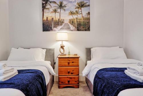 a bedroom with two beds and a table with a lamp at Cosy 2 Bedroom Flat Near Westcliff On Sea Beach & Hamlet Court Road in Southend-on-Sea