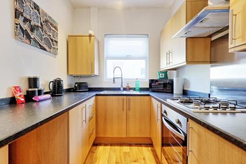 a kitchen with wooden cabinets and a counter top at Cosy 2 Bedroom Flat Near Westcliff On Sea Beach & Hamlet Court Road in Southend-on-Sea
