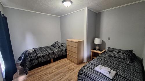 a bedroom with two beds and a dresser in it at Central Apartment, Steps from the Park in Oswego