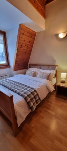 una camera da letto con un letto grande con testiera in legno di Private Apartment Lora - Aparthotel Vučko a Jahorina