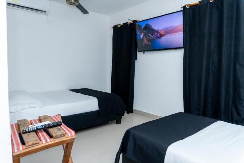 a room with two beds and a flat screen tv at Neos Hotel Cartagena in Cartagena de Indias