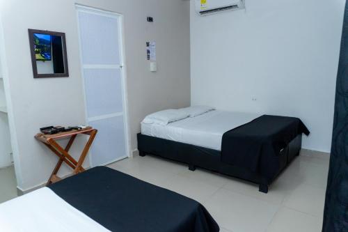 a small room with two beds and a table at Neos Hotel Cartagena in Cartagena de Indias
