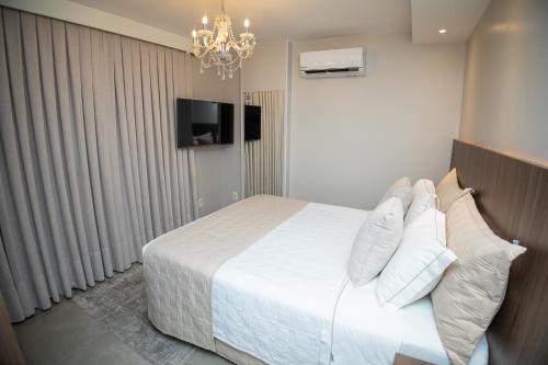 a bedroom with a bed with white sheets and pillows at Concept Hotel Flat in Balneário Camboriú