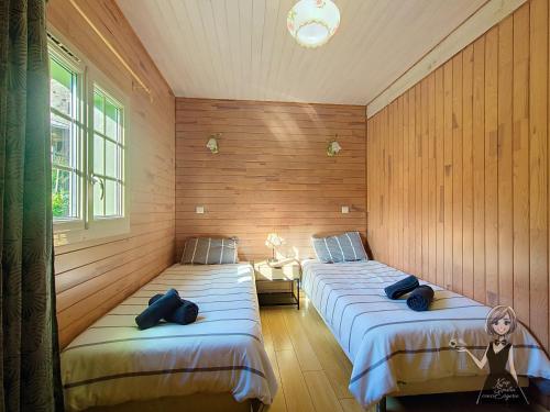 two beds in a room with wooden walls at Chalet Tulasi, douceur et sérénité à Eysus in Eysus