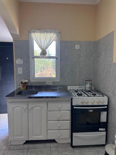 Una cocina con estufa, fregadero y ventana. en Bungalows El Amanecer, en Colón