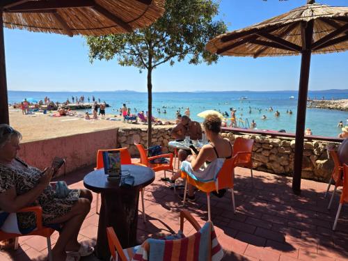 un gruppo di persone seduti su sedie in spiaggia di Apartments Lora a Vir (Puntadura)