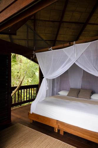 a bed in a room with a mosquito net at Irana Pacific Hotel in Nuquí