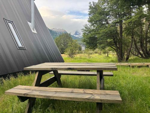 OUTSCAPE l Cabaña Familiar en mejor sector de Cerro Castillo في فيلا سيرو كاستيلو: طاولة نزهة خشبية للجلوس بجوار مبنى