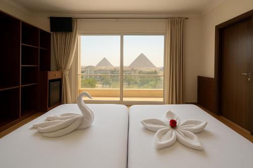 two swans sitting on a bed with a flower on it at King's Gate pyramids & sphinx view hotel in Cairo
