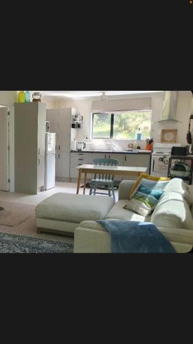 a living room with a couch and a table in a kitchen at Mikimiki Valley Cottage near Tararua Park Trailhead in Masterton