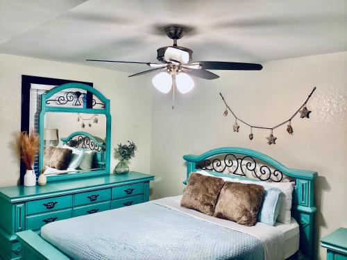 a bedroom with a blue bed and a ceiling fan at Urban Aquarium Home for 8 in Galveston