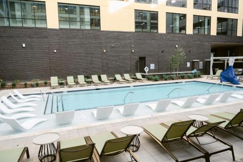 a large swimming pool with chairs at Anthem House Huntsville MidCity, powered by Placemakr in Huntsville