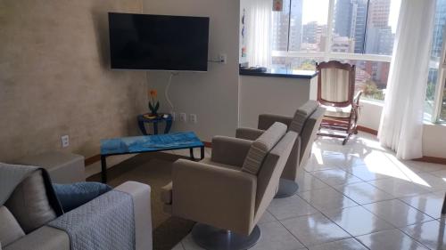 托雷斯APARTAMENTO SOLAR DA PRAÇA, Aconchegante e Climatizado的客厅配有椅子和平面电视