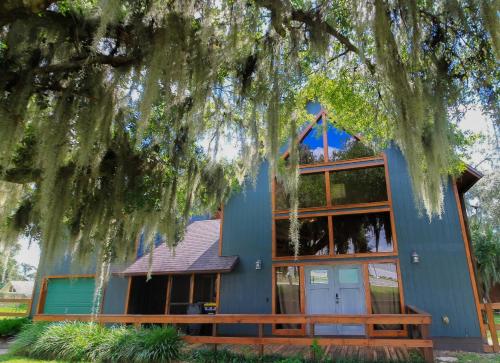 una casa blu con un albero di fronte di Serene Lakeside Retreat- 3 Bdr Romantic Getaway a Winter Haven