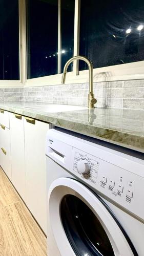 Una lavadora blanca en una cocina con fregadero. en Irooms770, en Haifa