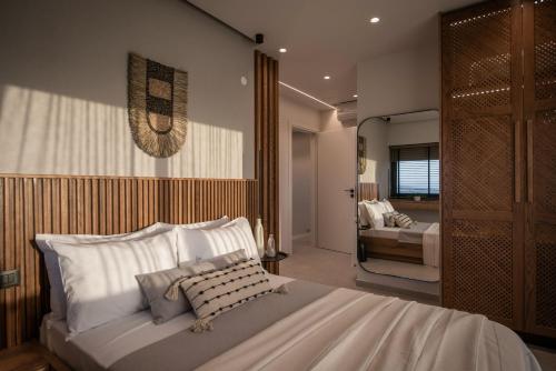 a bedroom with a large white bed and a room with a bed sqor at Brand new Petra Luxuria Villa with private pool in Prasás