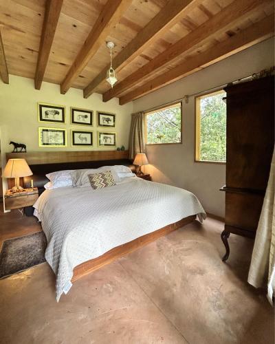 a bedroom with a large bed and two windows at Rancho el Capricho in Valle de Bravo
