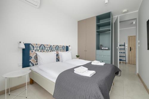 ein Schlafzimmer mit einem großen Bett mit zwei Handtüchern darauf in der Unterkunft GREENERI PARK - Ambria Apartments in Świnoujście