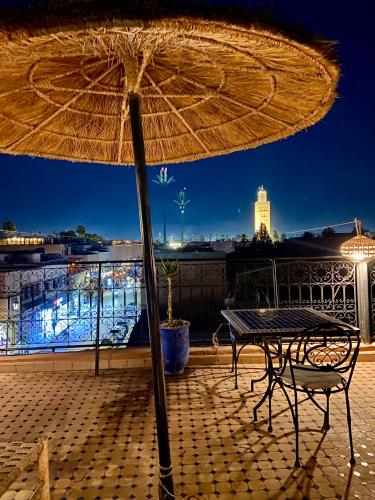 ein Tisch und Stuhl unter einem Sonnenschirm auf einem Balkon in der Unterkunft Dar Koutobia Stars in Marrakesch