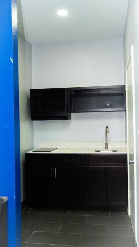a kitchen with black cabinets and a sink at Airway Inn - IAH Airport in Houston