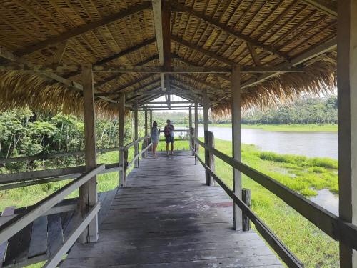 two people walking on a wooden bridge over a river at Residencial Romulo AP 3 in Manaus