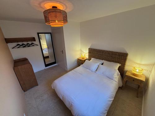 a bedroom with a white bed with two tables and a mirror at La Croix Perette in Azay-le-Rideau