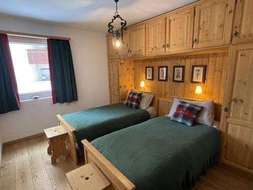 2 Betten in einem Zimmer mit Holzschränken und einem Fenster in der Unterkunft Sankt Moritz Chesa Ruinatsch 50 in St. Moritz