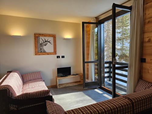 Una sala de estar con dos sofás y una puerta corrediza de vidrio. en Cimaboschi, en Sestriere