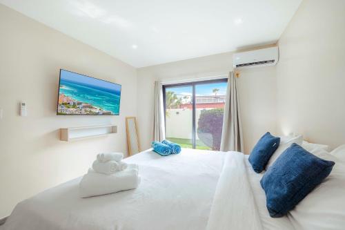 a bedroom with a white bed with a tv on the wall at Palm Beach Sea La Vie Suites in Palm-Eagle Beach