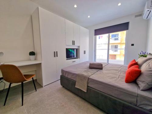 Luxury Qawra Holiday Stay Apartment في خليج سانت بول: غرفة نوم بسرير كبير مع كرسي ونافذة