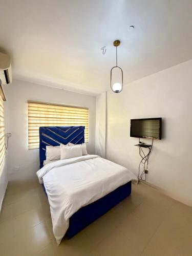 sypialnia z niebiesko-białym łóżkiem i telewizorem w obiekcie Crestal Resorts w mieście Magodo