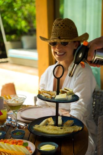 een vrouw met een cowboyhoed op en een fles wijn in haar hand bij Umbelina Pousada Boutique in Porto De Galinhas