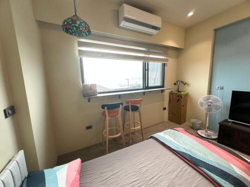 ein Schlafzimmer mit einem Bett, einem Fenster und zwei Hockern in der Unterkunft 漾漾漫旅Young B&B in Fang-liao