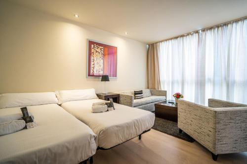 a hotel room with two beds and a couch at Abba Huesca in Huesca