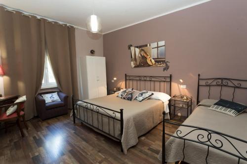 ein Schlafzimmer mit zwei Betten und einem Stuhl in der Unterkunft Segui le note della Tua vita in Cremona