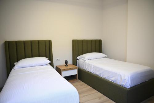 a room with two beds and a table with a night stand at The Minimalist Escape II in Kamëz