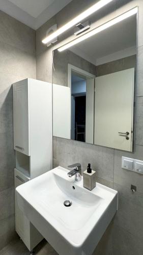 a bathroom with a white sink and a mirror at VENUS Studios at Coresi Mall in Braşov