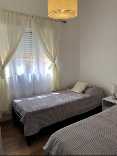 Un dormitorio con dos camas y una ventana. en Casa a 3 cuadras del mar- Piriápolis, en Piriápolis