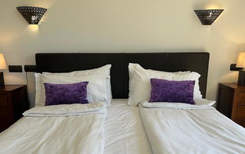 two pillows on a bed with white sheets and purple pillows at Beachhouse 2min to the sea with pool & wonderful garden in Calvia Town