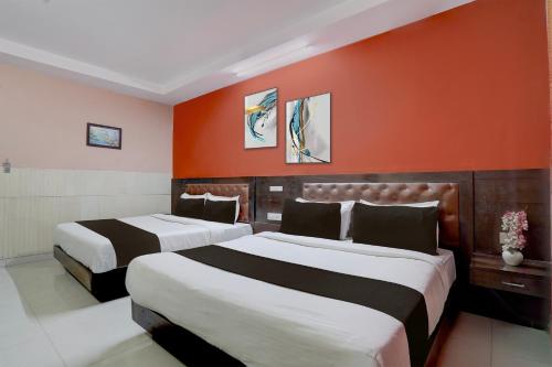 Dos camas en una habitación de hotel con una pared naranja. en Collection O Haridwar Railway Station Formerly Le Central, en Haridwar