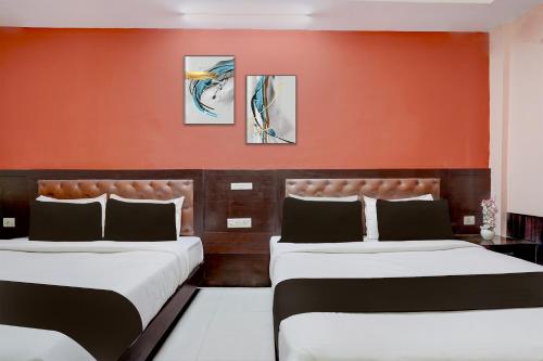 Dos camas en una habitación con una pared naranja. en Collection O Haridwar Railway Station Formerly Le Central, en Haridwar